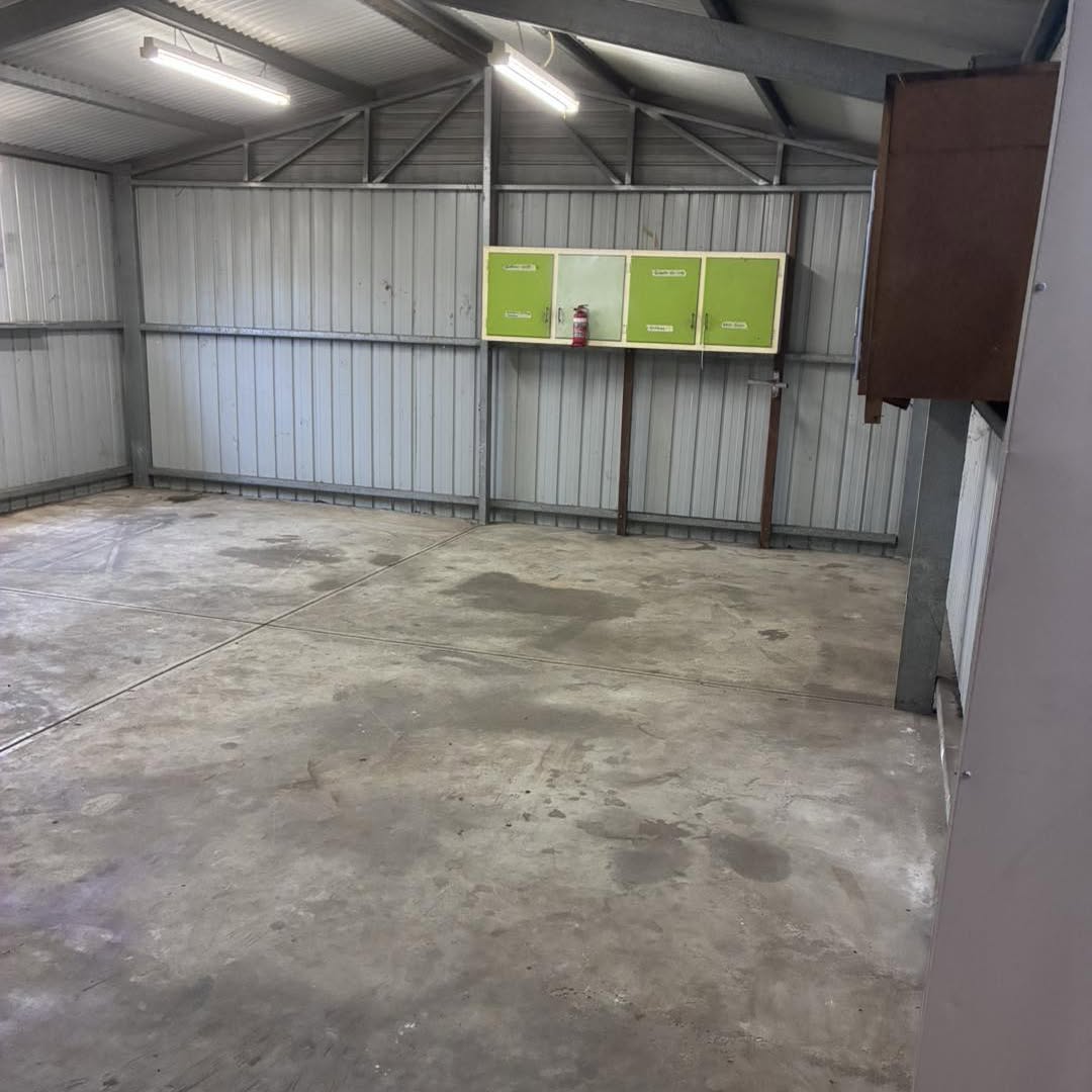 The same shed emptied, with the green cabinets back on the wall and the floor swept