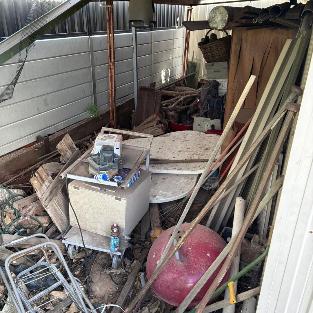 Side passage piled with timber, pipes, an old table and household junk