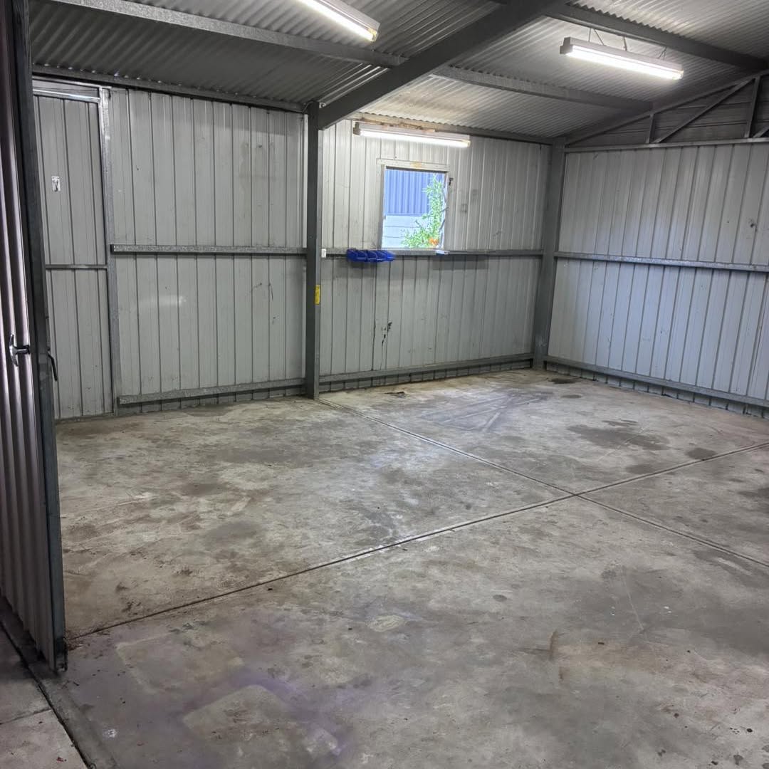 An empty steel shed with a swept concrete floor after a clear out
